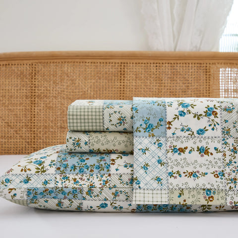 Close up stack of folded cotton patchwork fitted sheet and pillowcases with rattan headboard	