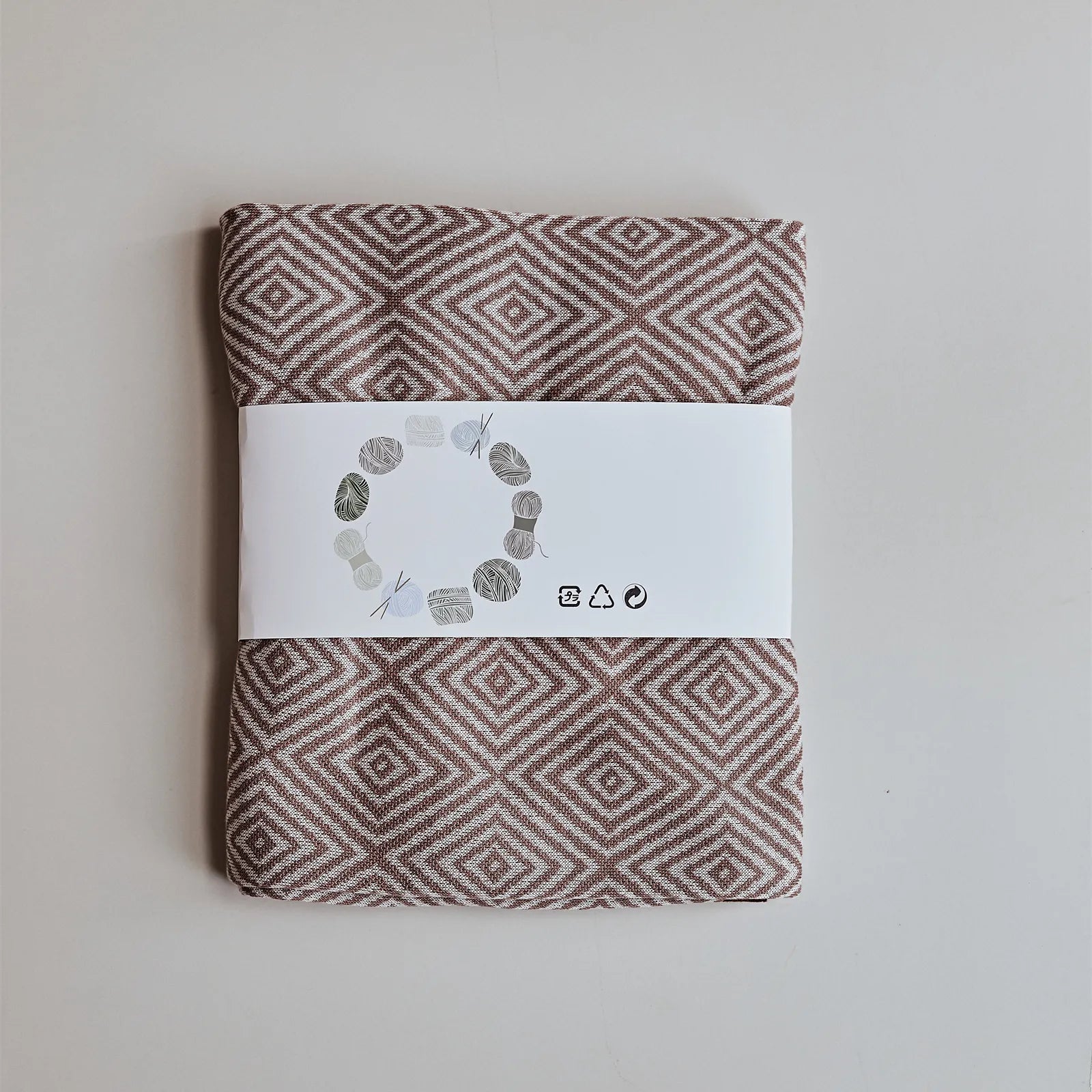Folded dusty-pink diamond throw blanket with retail band packaging, showing the pattern clarity.