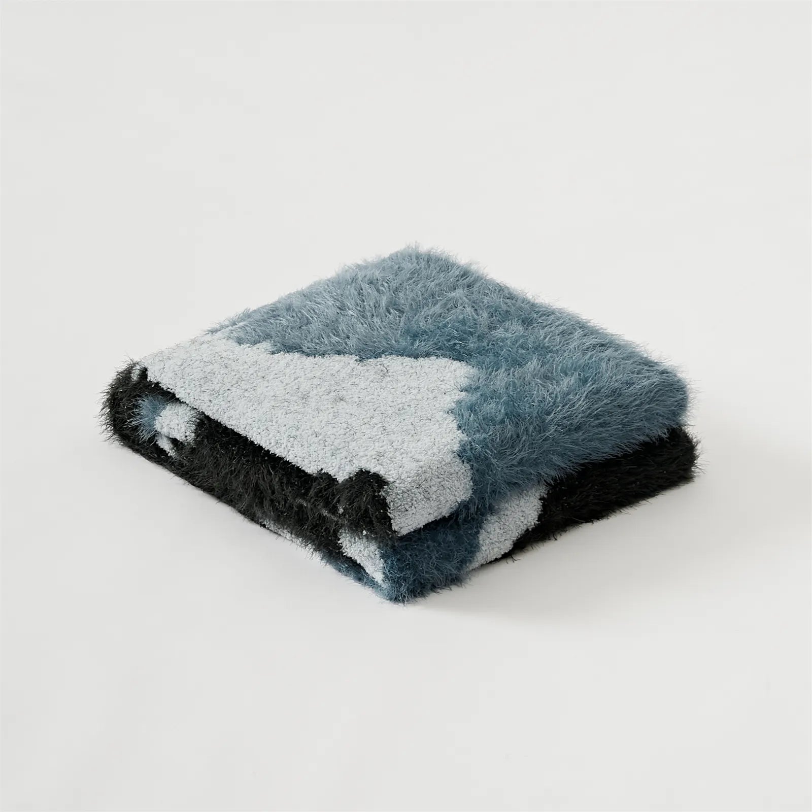 Neatly folded abstract fuzzy knit throw blanket in teal and black studio shot
