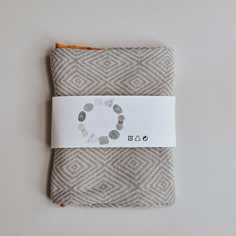 Folded light-grey diamond pattern throw blanket with retail band packaging, showing the yellow border detail.