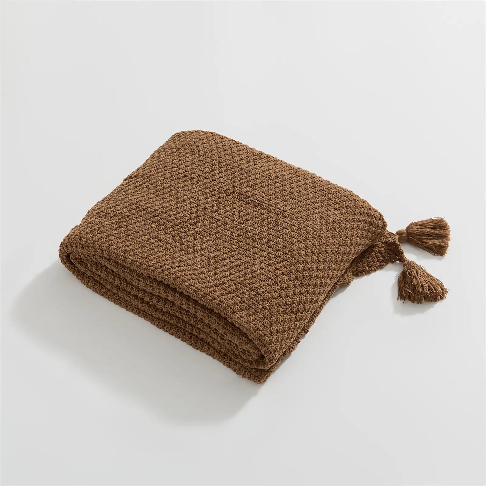 Folded Mocha Knitted Throw Blanket Showing Tassel on White Background