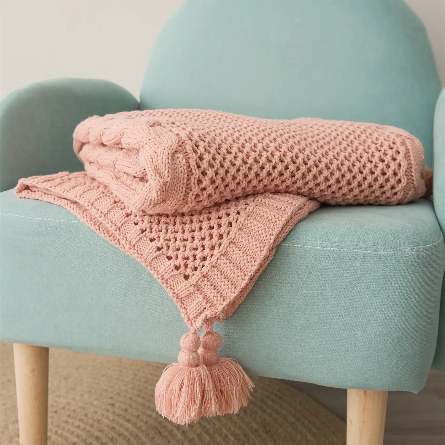 Folded Rose Pink Throw Blanket Neatly Placed on Teal Accent Chair