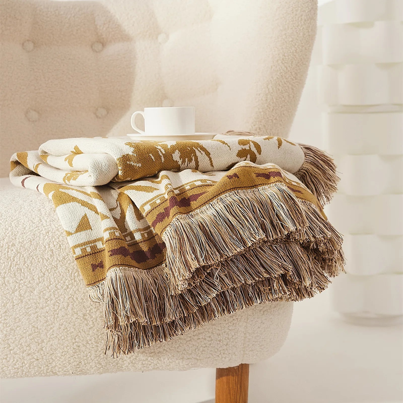  A neatly folded sand yellow bohemian tassel blanket, showcasing its warm color and soft woven texture.