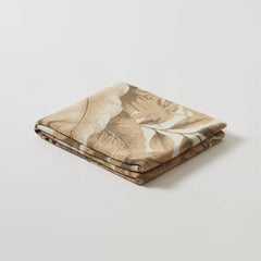 A neatly folded forest-inspired blanket, perfect as a lightweight throw for your couch or bed.
