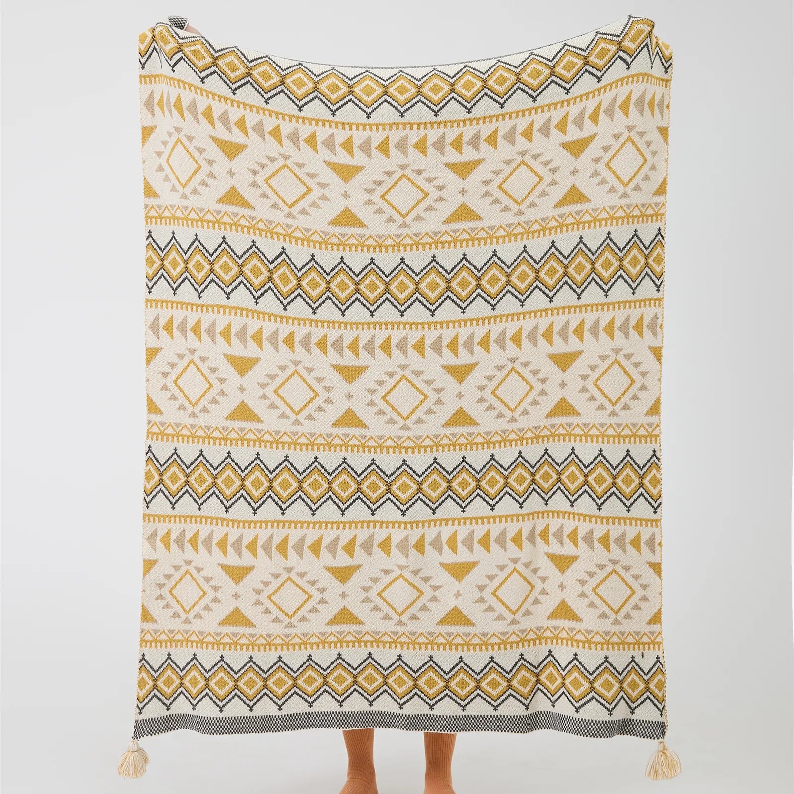 Full size boho geometric knit throw blanket with tassels in mustard yellow and cream studio shot