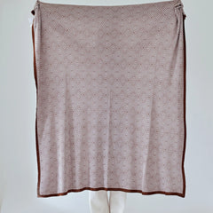 Full view of the large dusty-pink diamond pattern throw held up, showing the full geometric pattern and dark border.