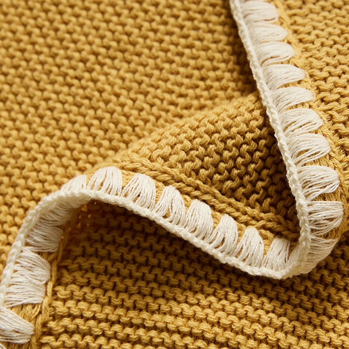 Close up of the ginger yellow cotton throw edge showing the white contrast fringe trim