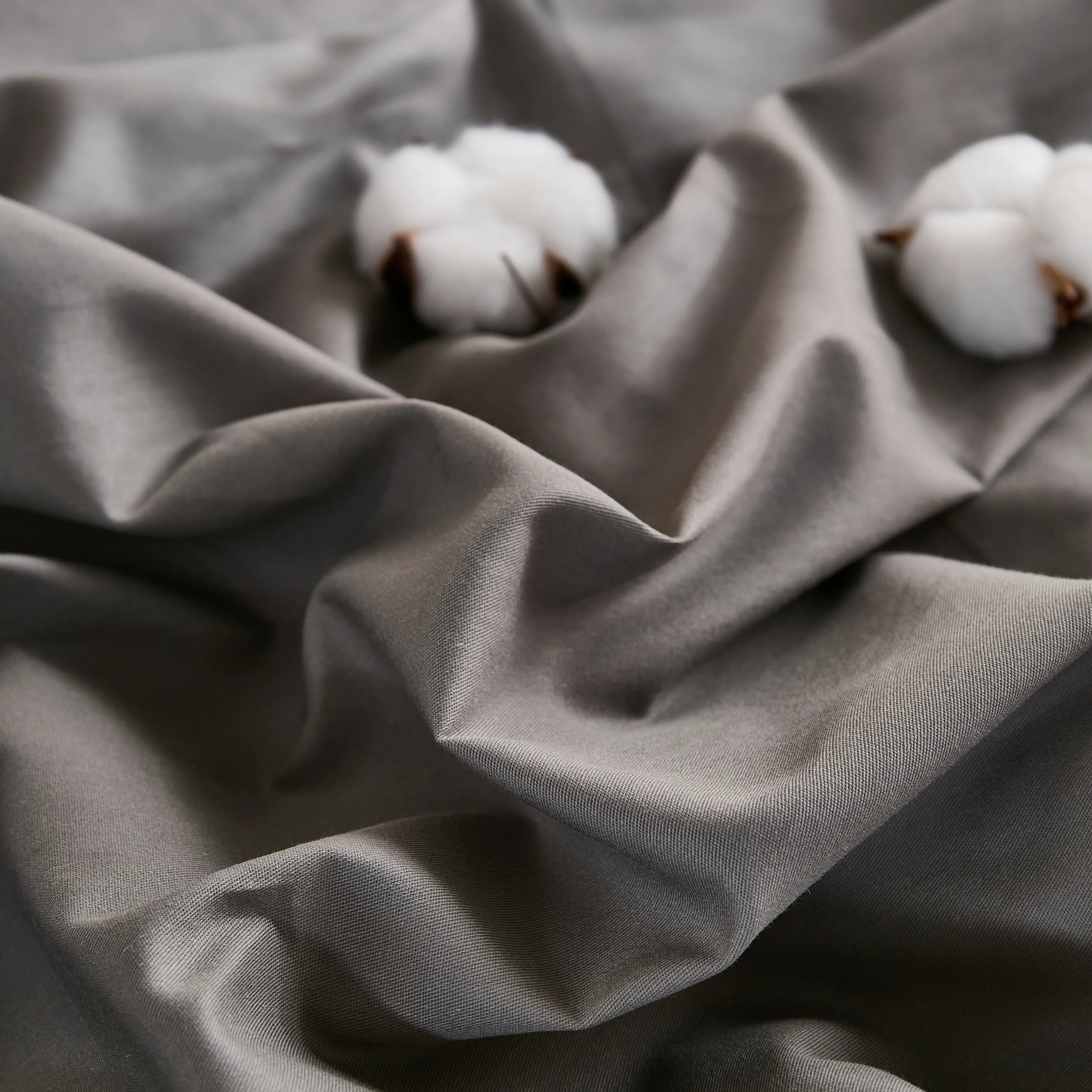 Gray fabric texture detail with two cotton pieces on wrinkled surface