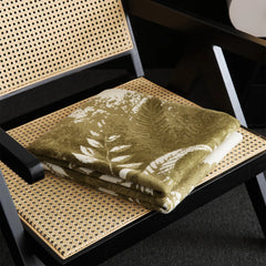  A folded view of the green forest landscape blanket on the chair