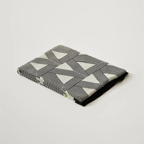 A studio shot of a perfectly folded geometric blanket, showcasing its clean design and green accents.