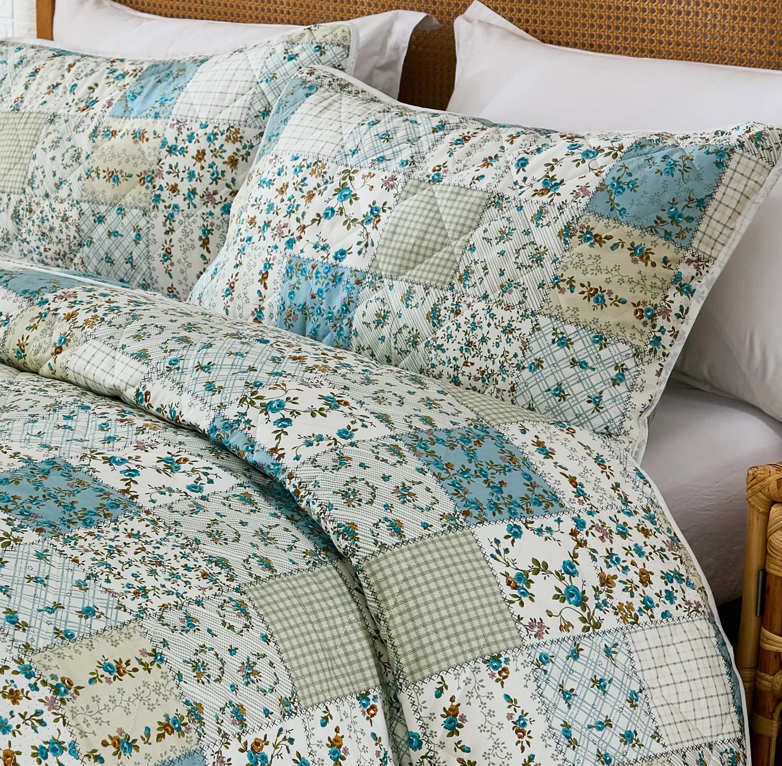 Close-up of the quilt and pillows showing the various green and blue patchwork patterns.