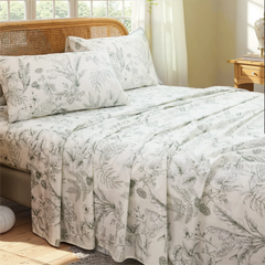 Cotton greenery botanical sheet set draped on bed with leaves print and natural light