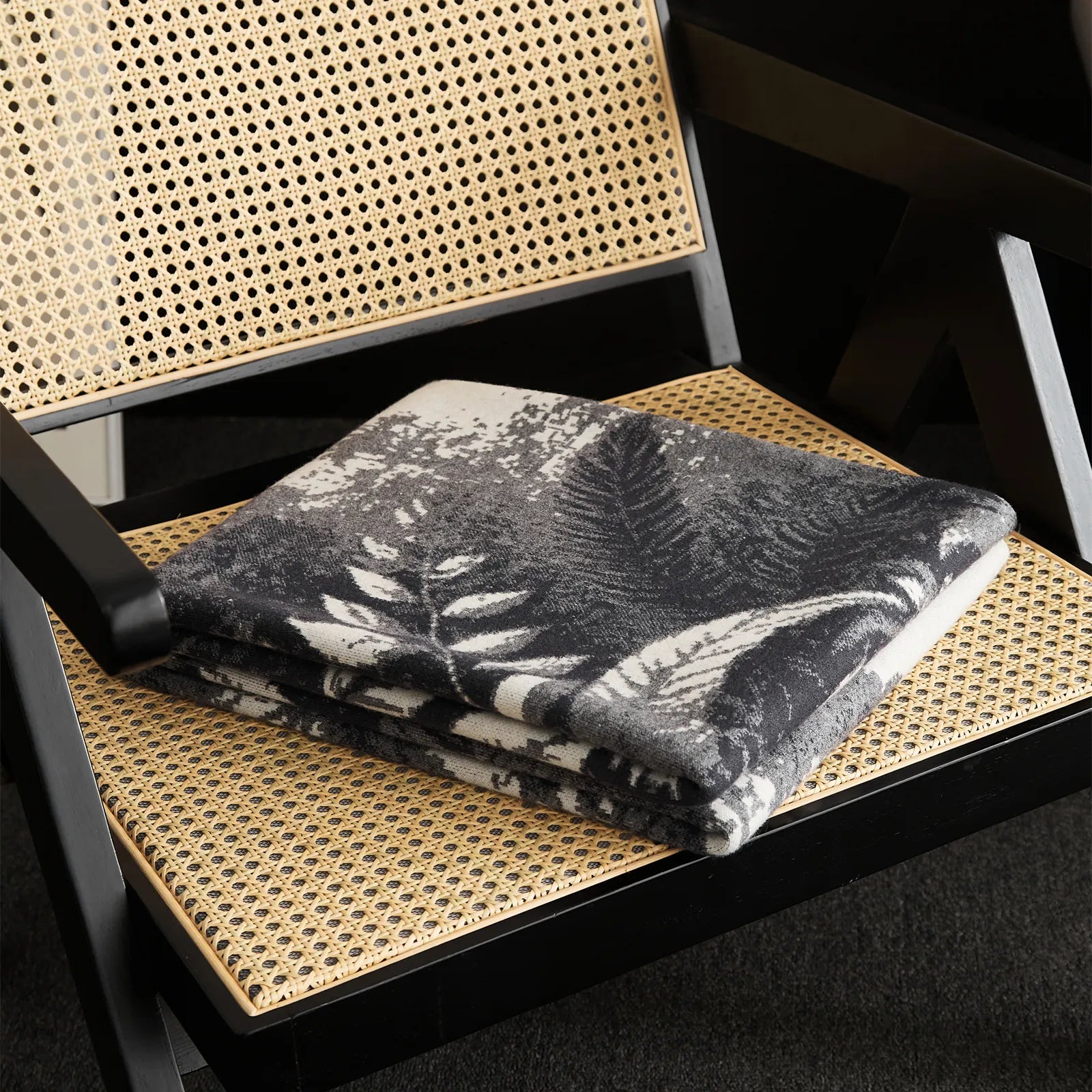  A folded view of the grey forest landscape blanket on the chair