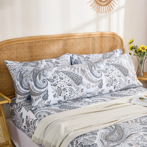 A complete view of a bed styled with two standard and one long grey paisley cotton pillowcases, showcasing a full bedding set.