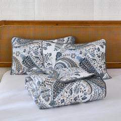 The grey paisley quilt set neatly folded on a bed for display.