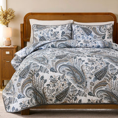 The grey paisley quilt set on a bed, showing the whole bedroom scene.