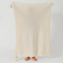 Person Holding Up Beige Knitted Throw Blanket with Tassels Full View