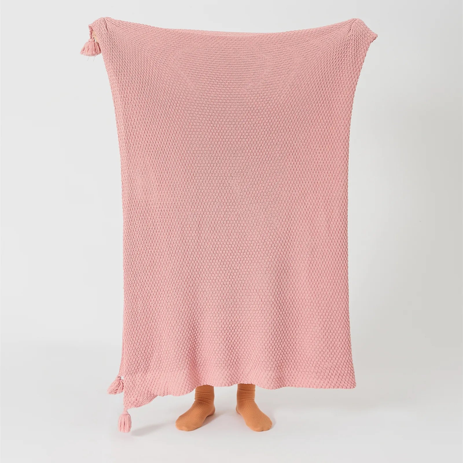 Person Holding Up Pink Knitted Throw Blanket with Tassels