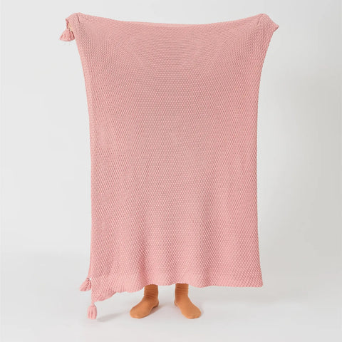 Person Holding Up Pink Knitted Throw Blanket with Tassels