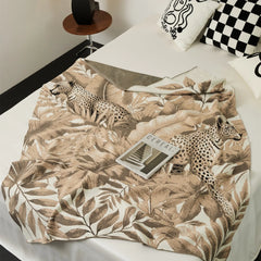 The Forest-Inspired blanket styled neatly on a bed, with a stack of books for a cozy and inviting bedroom look.