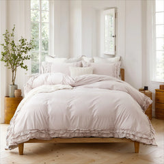Lavender cotton double ruffle duvet cover on a light wooden platform bed with pillows, near a window with four panes.