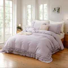 Lavender cotton ruffle duvet cover and pillows on a bed between two nightstands with a lamp and books.