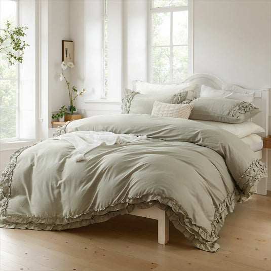 Light gray cotton double ruffle duvet cover on a bed with pillows, a white vase with plants, and simple wall art.