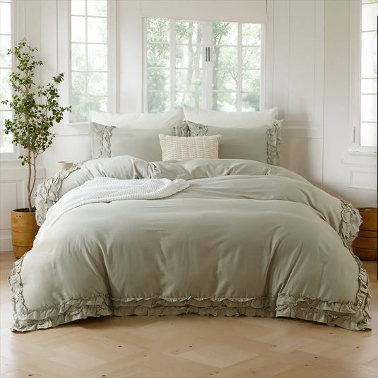 Light gray cotton double ruffle duvet cover with a woven texture pillow and a plant in a brown pot by a sunny window.