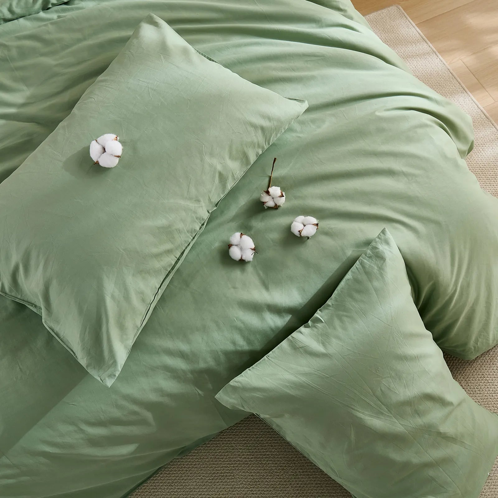 Top layout of light green duvet with four cotton blooms and two pillows