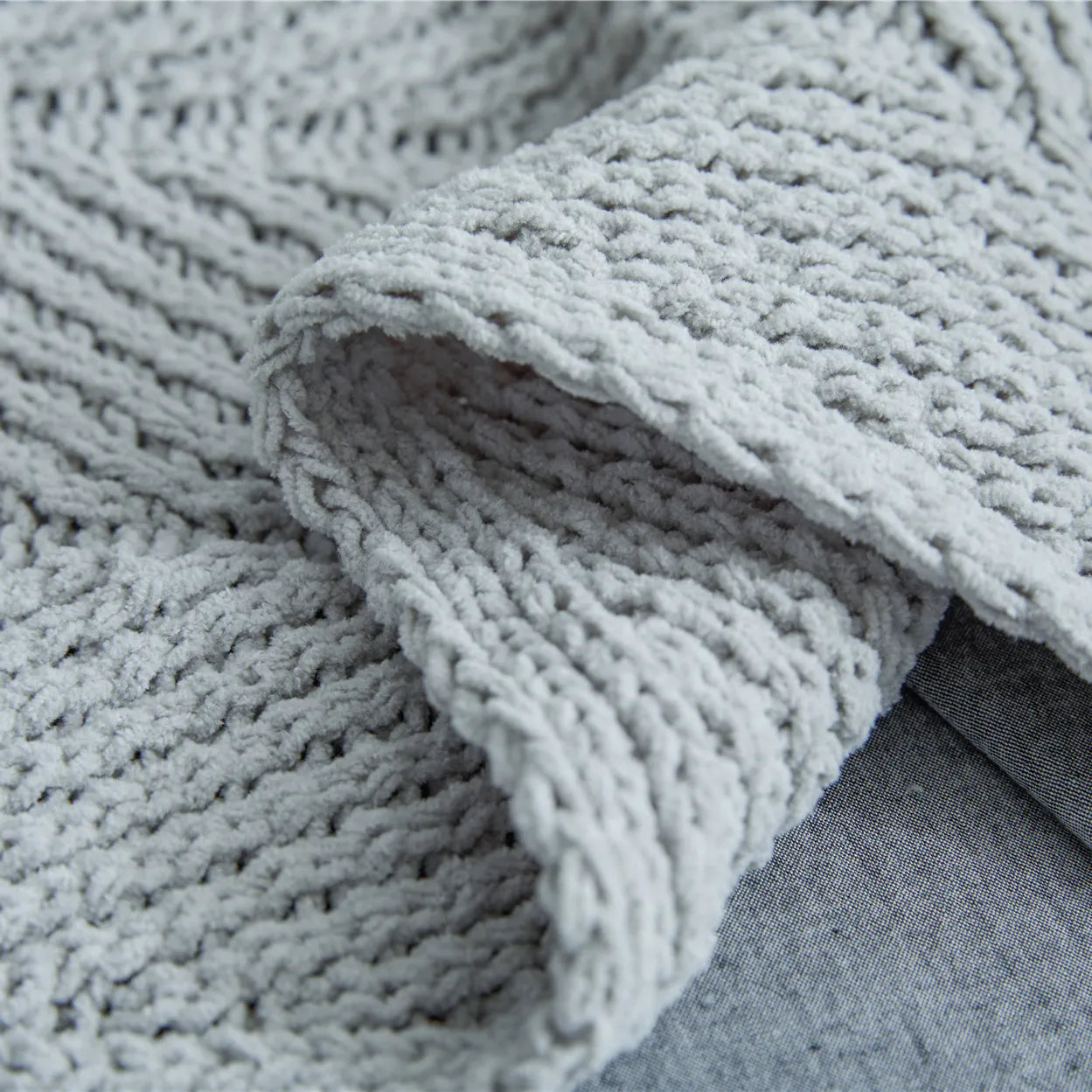 Close up detail of light heather grey chunky knit fabric texture and soft weave