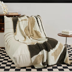 Luxury fluffy abstract pattern knit blanket in mocha taupe and cream on white modern accent chair