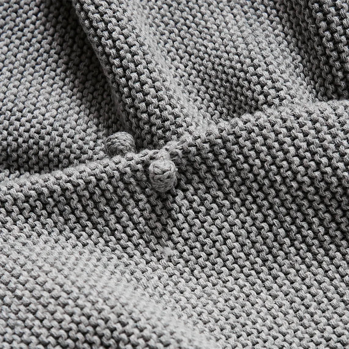 Close up detail of the textured medium grey cotton knit fabric showing the bobble pattern