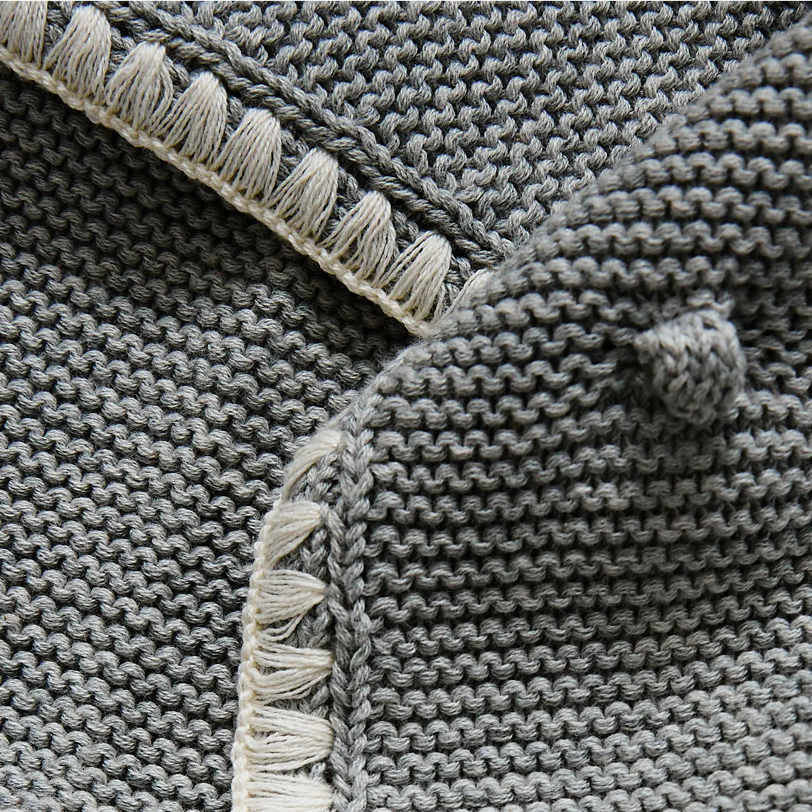 Close up of the medium grey cotton knit fabric and the cream decorative fringe trim