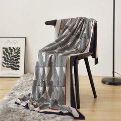 A modern geometric wool throw blanket draped over a chair, adding a sophisticated element to a room.