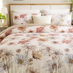 Overhead view of watercolor floral duvet cover with multiple coordinating pillows and bedside lamp