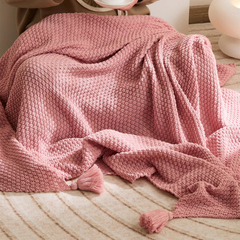 Close-up of Pink Knitted Throw Blanket Used by Person Showing Tassels