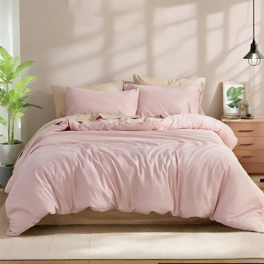 Front flat-lay view of a pink solid cotton duvet fully spread on the bed with pillows on both sides, soft natural light from the window.