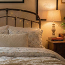 detailed shot of poetic meadow floral bedding under the warm glow of a bedside lamp
