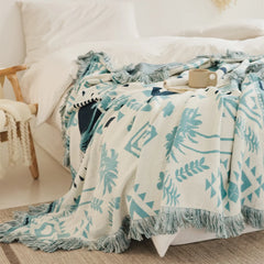 A neatly folded Prussian blue bohemian tassel blanket, ready to use as a cozy throw or decorative accent.
