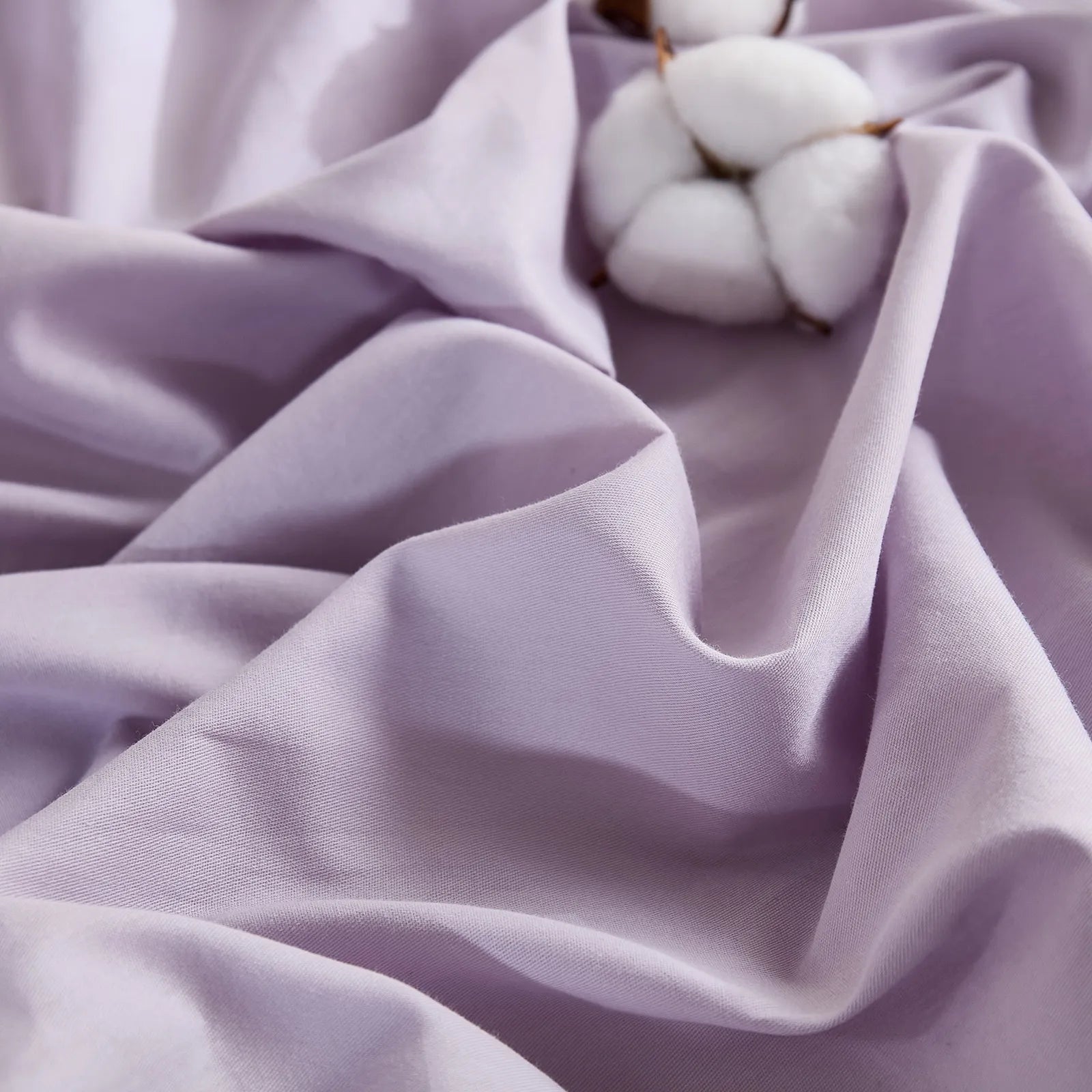Purple fabric with single cotton bloom detail on textured surface