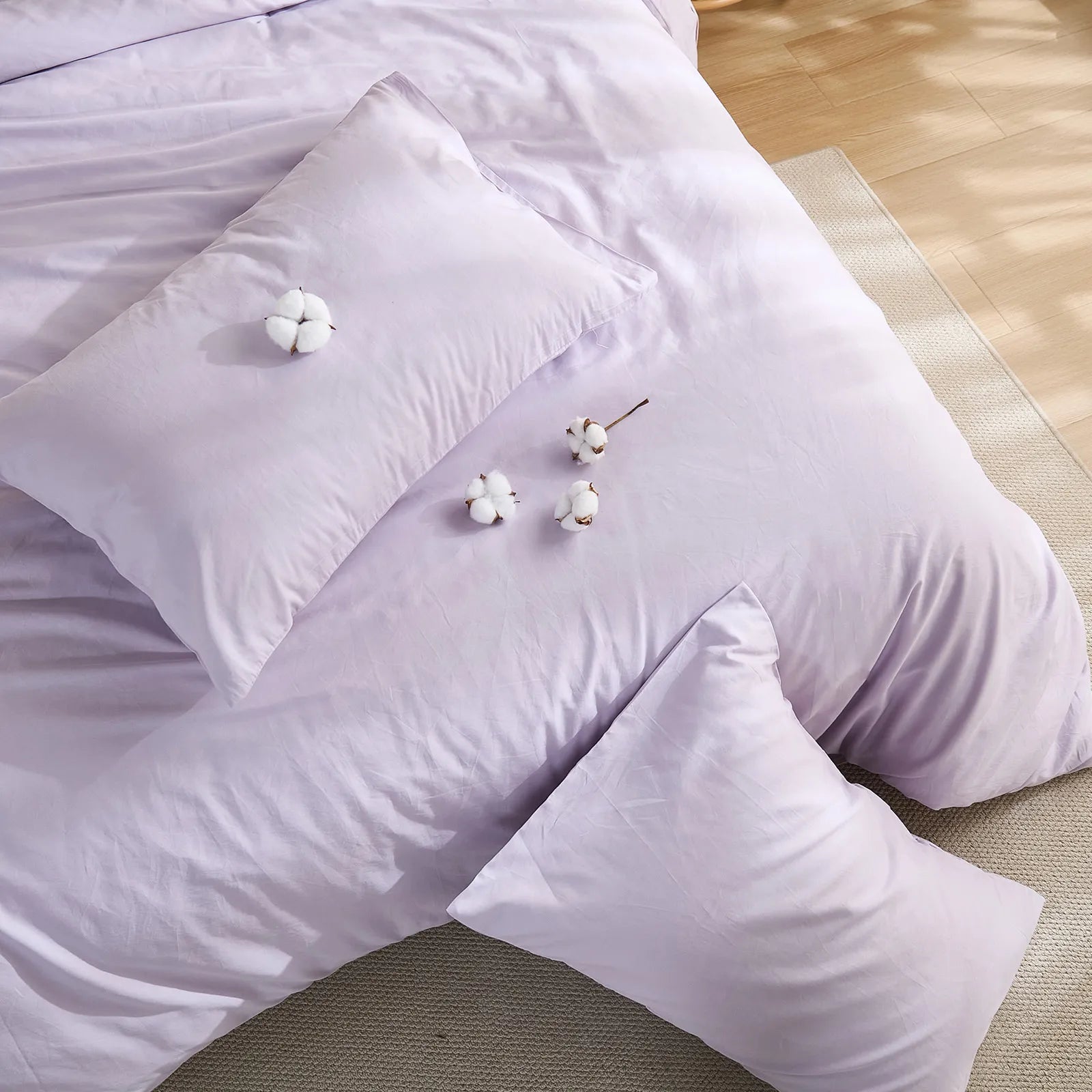 Purple solid duvet on bed with four cotton blooms and two pillows arrangement