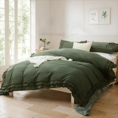 Sage green cotton double ruffle duvet cover on a white bed with a textured white throw pillow and wall art.