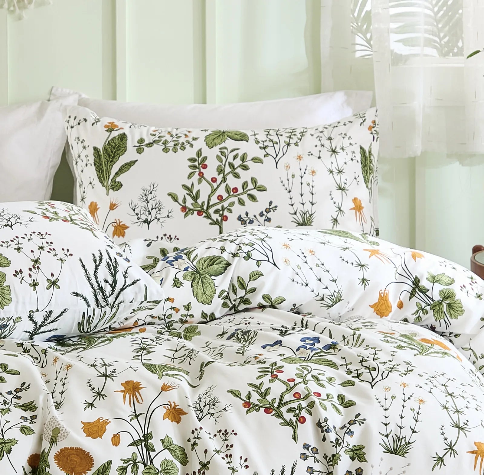 A detailed close-up of the fabric texture and pattern of the sage green floral bedding