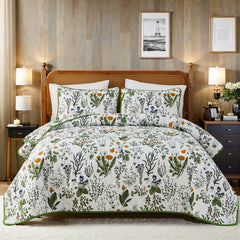 A full view of the sage green floral quilt set on a bed with pillows.