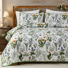 Full view of the sage green floral quilt set styled on a bed.