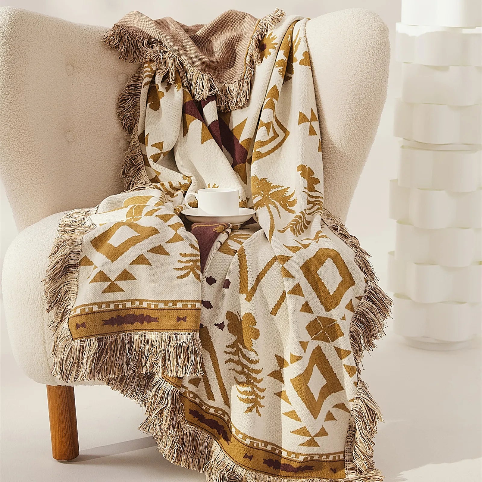 A Bohemian-style sand yellow cotton blanket draped over a light-colored couch, adding a touch of cozy texture to the room.