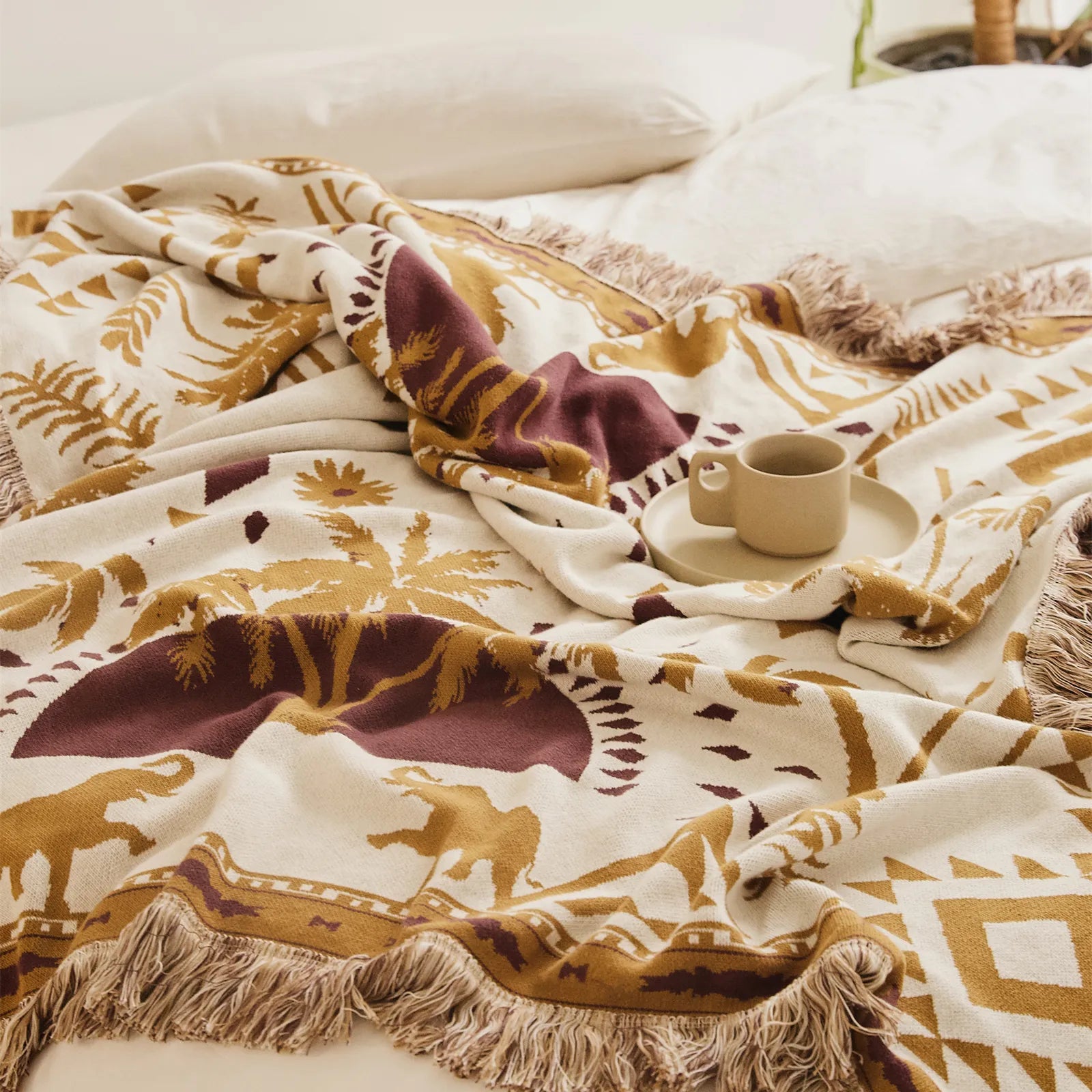 A cozy sand yellow cotton tassel blanket draped over a bed with a matching pillow, creating a warm, inviting look.