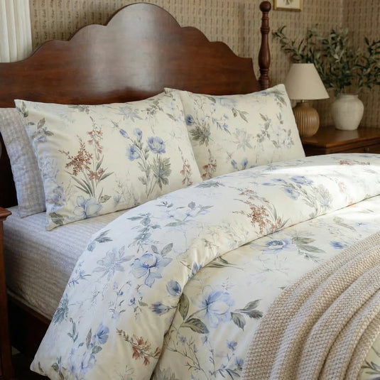 close-up of blue floral cotton bedding with warm bedside lamp and vintage wood furniture