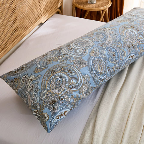 A side view close-up of a blue paisley cotton body pillow, showing the length and pattern detail against the white sheet.