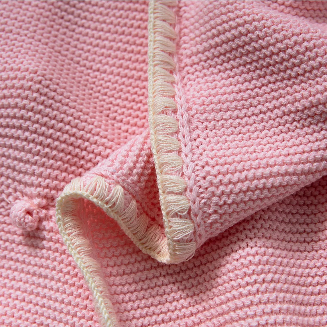 Close up of the soft pink cotton throw edge showing the cream contrast fringe trim